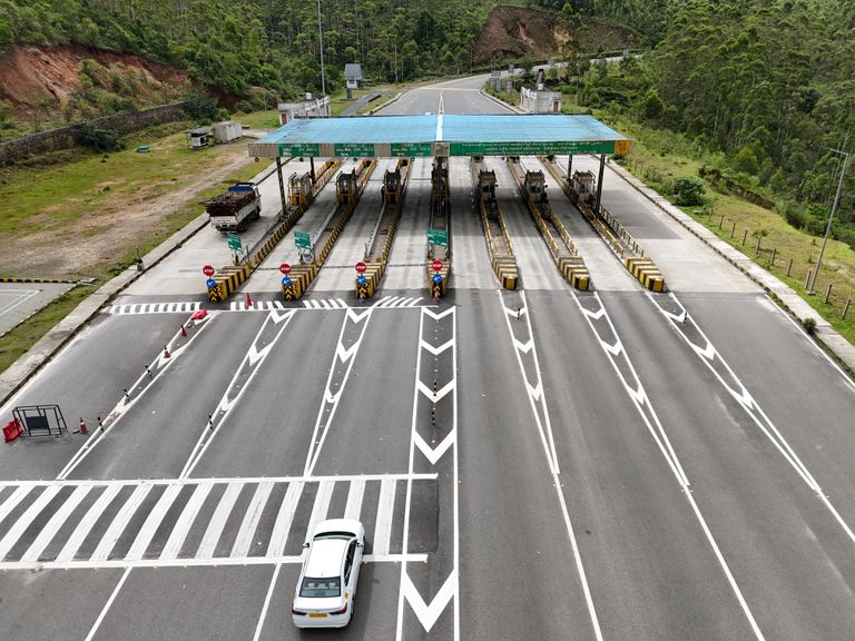 Praça de pedágio vista do alto, com a cobertura, as cabines e as faixas de acesso