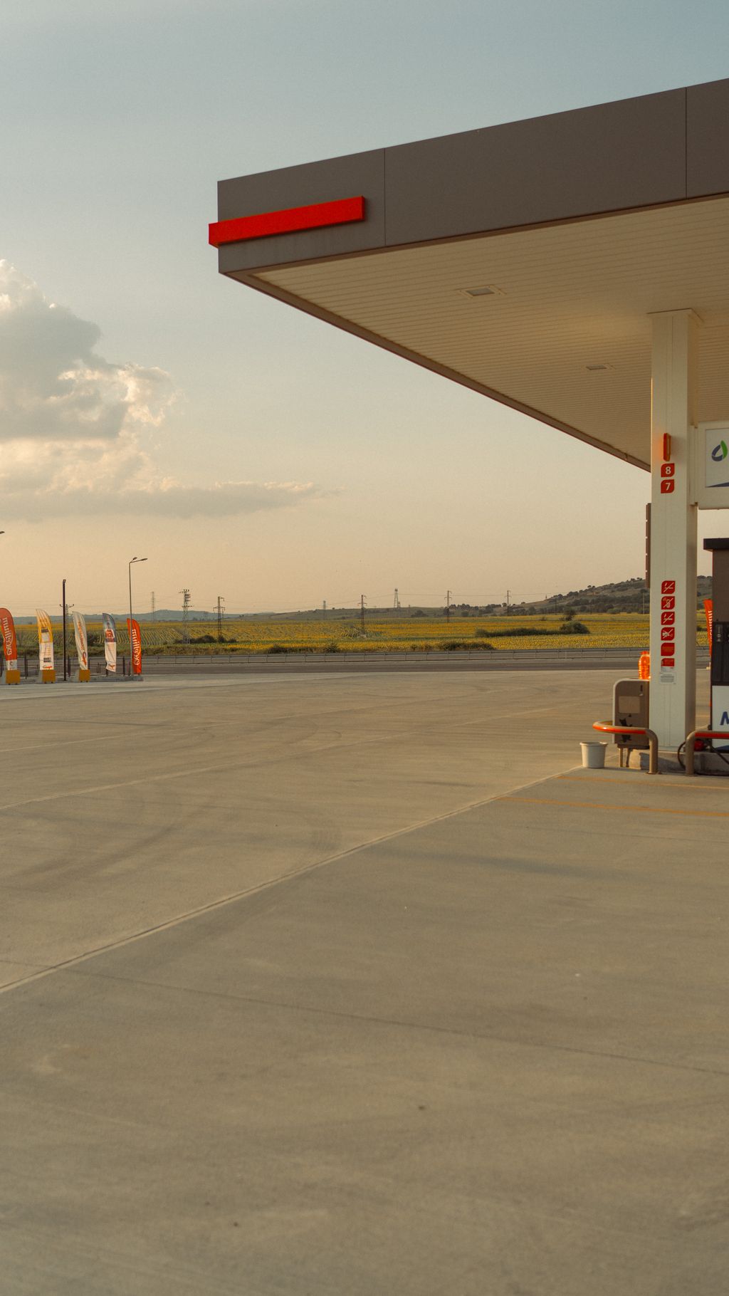 Posto de combustível à beira de uma rodovia, com a pista e o campo ao fundo