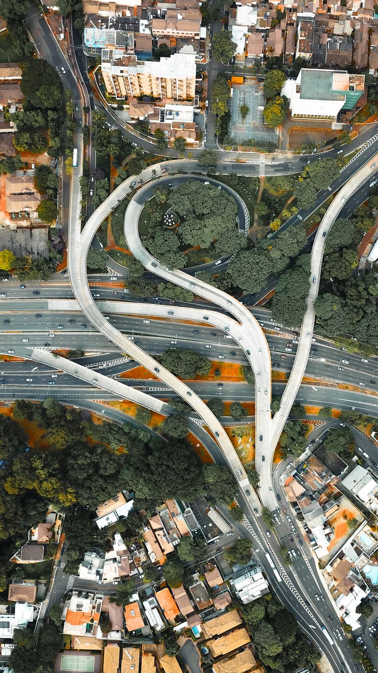 Viadutos e alças de um dispositivo em desnível numa avenida urbana, vistos de cima
