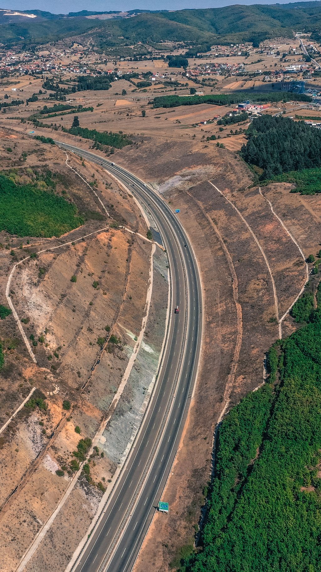 Rodovia de pista dupla em curva, vista do alto, com duas faixas por sentido