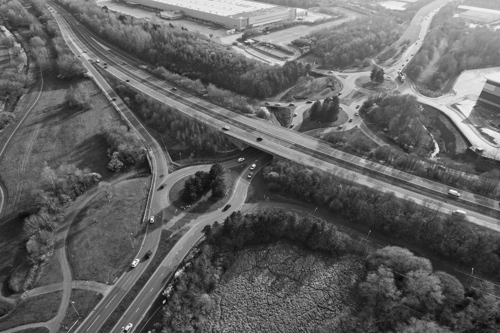 Malha viária vista do alto, em preto e branco: via expressa, viaduto e rotatórias interligadas