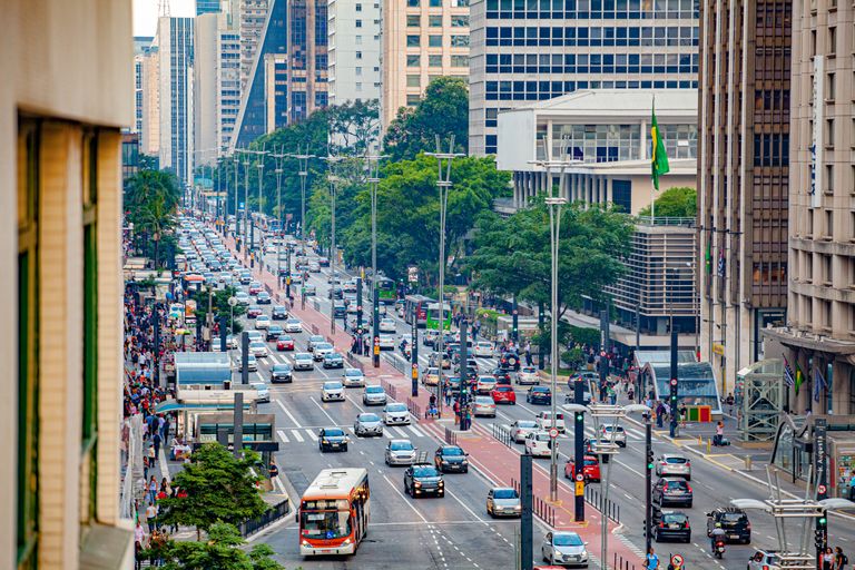Avenida movimentada vista do alto, com um ônibus urbano na faixa da direita