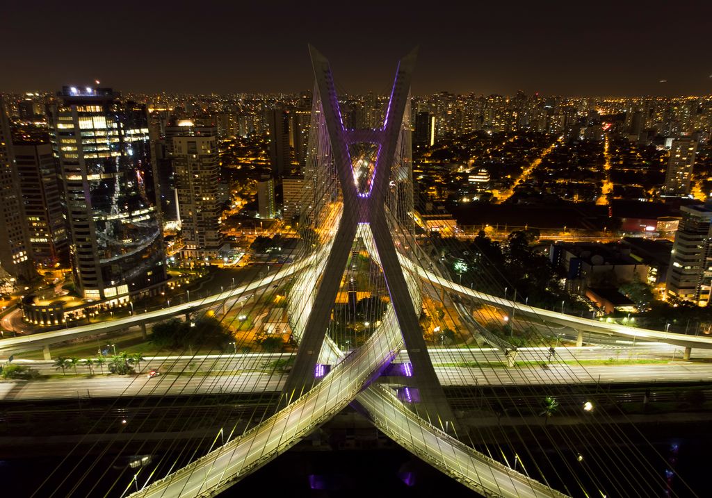 Ponte estaiada e alças da Marginal Pinheiros iluminadas à noite, em São Paulo, vistas do alto