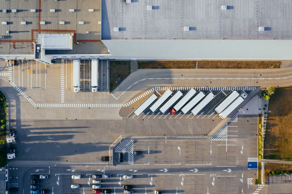 Pátio de caminhões junto a um centro logístico, visto do alto, com carretas em vagas inclinadas