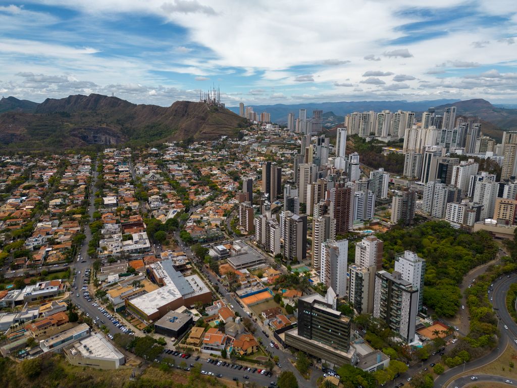Cidade vista do alto, com bairros, prédios altos, avenidas e a serra ao fundo