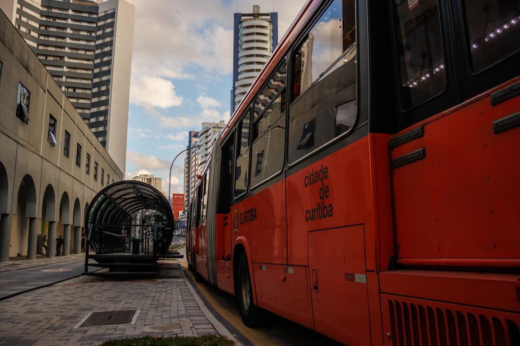 Ônibus articulado parado junto a uma estação de embarque em tubo